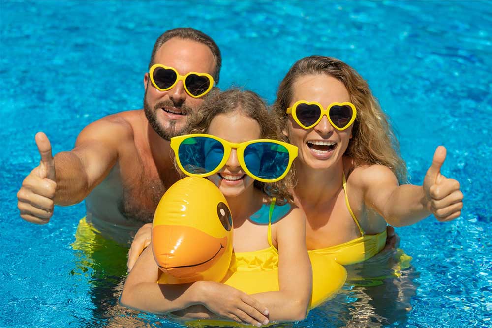 A family in the pool with their thumbs up